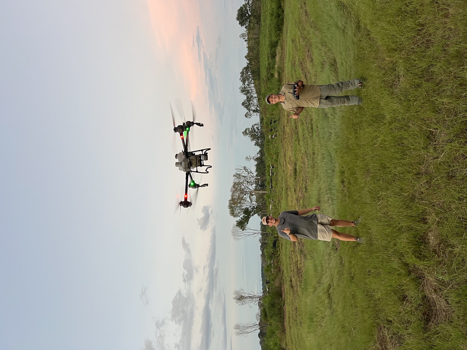 John and Carter flying the drone at sunset over green pasture
